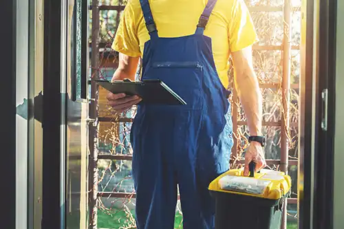 D&D Complete Sewer Service—A professional sewer worker in coveralls holding a clipboard and a toolbox outside a home in Lincoln, IL.